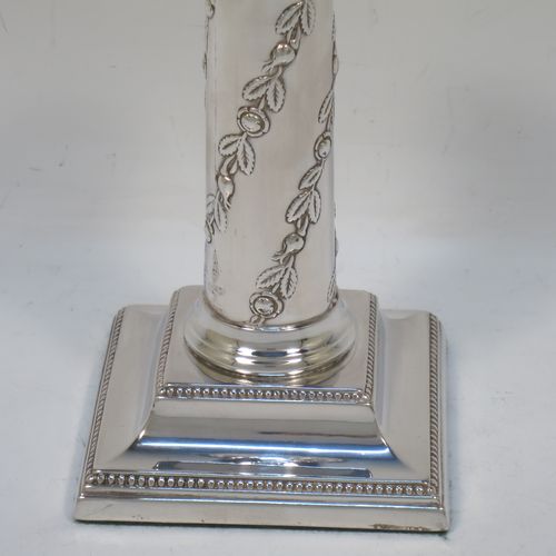 A very pretty Antique Edwardian Sterling Silver pair of candlesticks, in a Corinthian style with hand-chased floral and leaf decoration on the columns and bead-edged borders, removable nozzles, and square stepped bases. Made by Hawksworth, Eyre and Co., of Sheffield in 1909. The dimensions of this fine pair of hand-made antique silver candlesticks are height 13 cms (5 inches), and the bases are 8 cms (3.25 inches) square.  