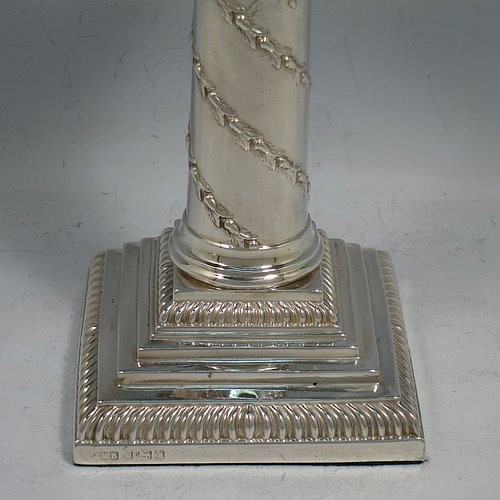 An Antique Victorian Sterling Silver pair of candlesticks, in the Corinthian style with gadroon-edged borders, removable nozzles, having columns with hand-chased garlands of flowers, and square stepped bases. Made by J. K. Bembridge of Sheffield in 1891. The dimensions of this fine pair of hand-made antique silver candlesticks are height 16 cms (6.25 inches), and the bases are 8.5 cms (3.3 inches) square.    