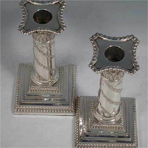 An Antique Victorian Sterling Silver pair of candlesticks, in the Corinthian style with gadroon-edged borders, removable nozzles, having columns with hand-chased garlands of flowers, and square stepped bases. Made by J. K. Bembridge of Sheffield in 1891. The dimensions of this fine pair of hand-made antique silver candlesticks are height 16 cms (6.25 inches), and the bases are 8.5 cms (3.3 inches) square.    