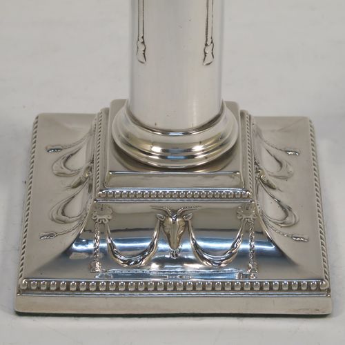 A very pretty Antique Victorian Sterling Silver pair of candlesticks, in a Neoclassical style with hand-chased bows, swags and rams heads, with bead-edged borders, round removable nozzles, and square  bases. This beautiful pair of antique silver candlesticks were made by William Gibson and John Langman (Goldsmiths and Silversmiths) of London in 1897. The dimensions of this fine pair of hand-made antique silver candlesticks are height 14 cms (5.5 inches), and the bases are 9 cms (3.5 inches) square.   