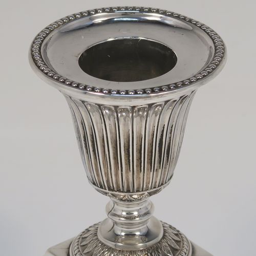 A small but very pretty pair of Antique Victorian Sterling Silver candlesticks, having urn-shaped bodies with fluted and anthemion leaf decoration, with applied bead-edged borders, sitting on square bases, and original removable nozzles. These beautiful silver candlesticks were made by Richard Hodd and Sons of London in 1877. The dimensions of these fine hand-made antique silver candlesticks are height 9 cms (3.5 inches), and the bases are 7.5 cms (3 inches) square.   