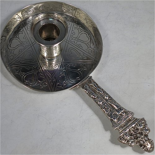 An Antique Victorian Sterling Silver Arts and Crafts style chamberstick, having a round hand-chased main body with raised border, with a central candle-holder and removable nozzle, and a cast medieval style figural handle. This beautiful copy of a 17th century style chamberstick was made by William Summers of London in 1877. The dimensions of this fine hand-made antique silver chamber-stick are length 24 cms (9.5 inches), diameter 12 cms (4.75 inches), and it weighs approx. 287g (9.3 troy ounces).