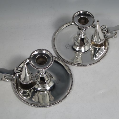 An Antique Georgian Sterling Silver pair of chamber-sticks, having plain round bodies, removable nozzles, original dunce-cap snuffers, and applied gadroon-edged borders. Made by Daniel Smith & Robert Sharp of London in 1788. The dimensions of these fine hand-made silver chambersticks are height 9 cms (3.4 inches), diameter 14 cms (5.5 inches), and they weigh a total of approx. 580g (18.7 troy ounces). Please note that both items are crested.    