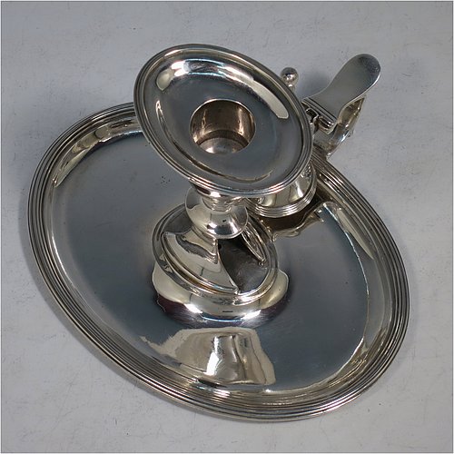 An Antique Georgian Sterling Silver chamber-stick, having an oval body, a plain scroll handle with thumb-piece, an original removable dunce-cap extinguisher, an original removable nozzle, and with applied reed-edged borders. Made by William Bennett of London in 1802. The dimensions of this fine hand-made antique silver chamberstick are width 16 cms (6.3 inches), depth 15 cms (6 inches), height 10 cms (4 inches), and it weighs approx. 319g (10.3 troy ounces).    