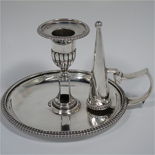 An Antique Georgian pair of Sterling Silver chambersticks, having plain round bodies with applied gadroon or rope-twist borders, with original removable nozzles and dunce-cap snuffers. Made by Richard Crossley of London in 1805. The dimensions of these fine hand-made antique silver chamber-sticks are height 10 cms (4 inches), diameter 13.5 cms (5.3 inches), and they weigh a total of approx. 677g (21.8 troy ounces).   