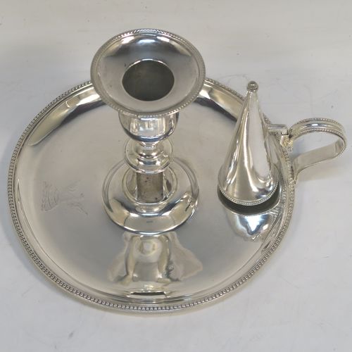 A very pretty Antique Georgian Sterling Silver chamber-stick, having a round base, a scroll handle, an original removable dunce-cap extinguisher, an original removable nozzle, and with applied bead-edged borders. This beautiful antique silver chamberstick was made by Hester Bateman of London in 1785. The dimensions of this fine hand-made silver chamberstick are diameter 15 cms (6 inches), height 11 cms (4.25 inches), and it weighs approx. 313g (10 troy ounces). Please note that this item is crested.