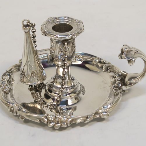 A very pretty Antique early Victorian Sterling Silver small chamber-stick for taper-stick size candles, having a round body with applied scroll and floral borders, a cast scroll handle, an original removable dunce-cap extinguisher with a security chain, and an original removable nozzle. This beautiful antique silver chamberstick was made by the Barnard Brothers of London in 1838. The dimensions of this fine hand-made silver chamberstick are diameter 9 cms (3.5 inches), height 5.5 cms (2.25 inches), and it weighs approx. 117g (3.8 troy ounces).  