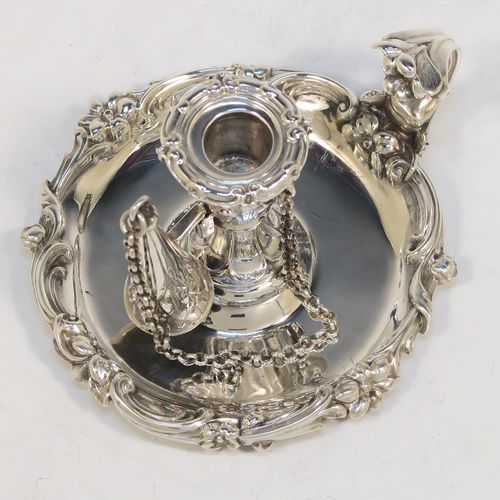 A very pretty Antique early Victorian Sterling Silver small chamber-stick for taper-stick size candles, having a round body with applied scroll and floral borders, a cast scroll handle, an original removable dunce-cap extinguisher with a security chain, and an original removable nozzle. This beautiful antique silver chamberstick was made by the Barnard Brothers of London in 1838. The dimensions of this fine hand-made silver chamberstick are diameter 9 cms (3.5 inches), height 5.5 cms (2.25 inches), and it weighs approx. 117g (3.8 troy ounces).  