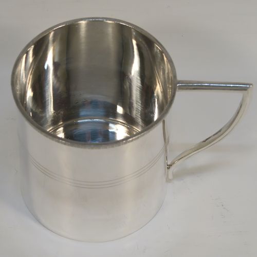 A very elegant Sterling Silver Georgian style christening mug, having a plain round body with a band of hand-chased reeded decoration, an applied egg and dart top border, a scroll handle with flat top, and sitting on a flat base. This handsome silver christening mug was made by Emile Viner of Sheffield in 1933. The dimensions of this fine hand-made silver christening mug are height 8 cms (3 inches), length 10 cms (4 inches), and it weighs approx. 137g (4.4 troy ounces).   