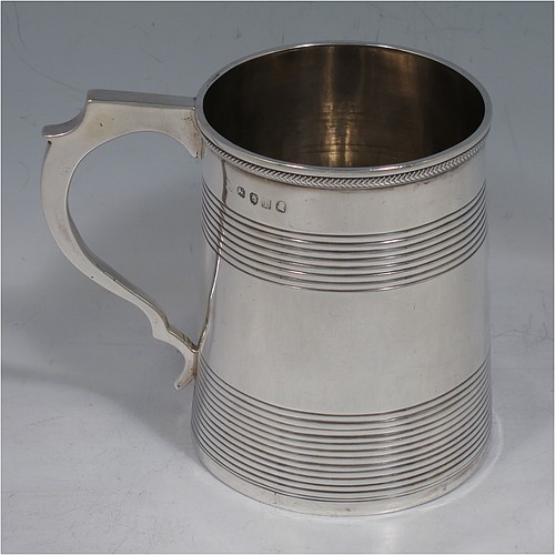 An Antique Georgian Sterling Silver christening mug, having a plain round body with two bands of hand-chased reeded decoration, an applied rope-twist top border, a scroll handle, and sitting on a flat base. Made in London in 1814. The dimensions of this fine hand-made antique silver christening mug are height 9 cms (3.5 inches), length 10 cms (4 inches), and it weighs approx. 129g (4.2 troy ounces).    