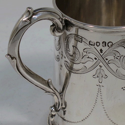 A very pretty Antique Victorian Sterling Silver christening mug, having a round body with straight sides, with hand-engraved floral and scroll decoration, applied bead-edged borers, a scroll handle, and sitting on a flat base. Made by the Alexander Macrae of London in 1864. The dimensions of this fine hand-made antique silver christening mug are height 9.5 cms (3.75 inches), diameter at lip 6.5 cms (2.5 inches), and it weighs approx. 157g (5 troy ounces).  