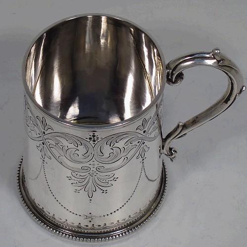 A very pretty Antique Victorian Sterling Silver christening mug, having a round body with straight sides, with hand-engraved floral and scroll decoration, applied bead-edged borers, a scroll handle, and sitting on a flat base. Made by the Alexander Macrae of London in 1864. The dimensions of this fine hand-made antique silver christening mug are height 9.5 cms (3.75 inches), diameter at lip 6.5 cms (2.5 inches), and it weighs approx. 157g (5 troy ounces).  