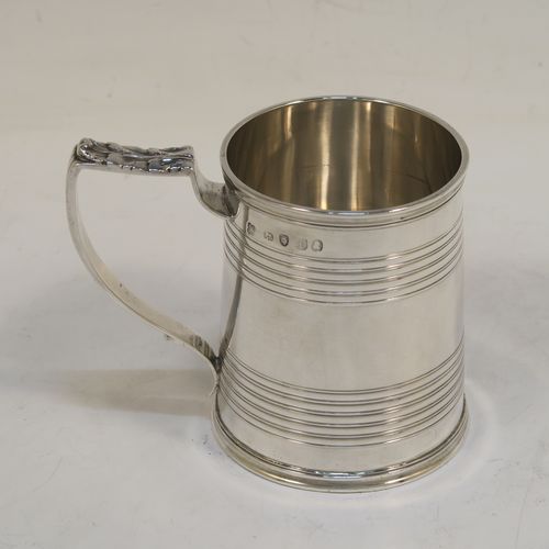 An elegant Antique Georgian Sterling Silver christening mug, having a plain round body with two bands of hand-chased reeded decoration, a scroll handle with an applied anthemion leaf thumb-piece, and sitting on a flat base. This handsome antique silver christening mug was made by Emes and Barnard in London in 1821. The dimensions of this fine hand-made antique silver christening mug are height 7.5 cms (3 inches), length 9 cms (3.5 inches), and it weighs approx. 115g (3.7 troy ounces).  