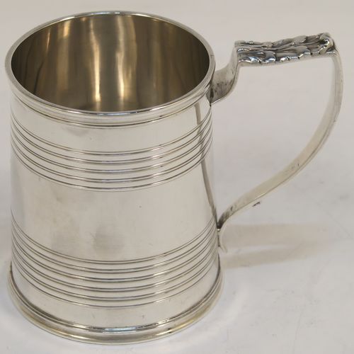 An elegant Antique Georgian Sterling Silver christening mug, having a plain round body with two bands of hand-chased reeded decoration, a scroll handle with an applied anthemion leaf thumb-piece, and sitting on a flat base. This handsome antique silver christening mug was made by Emes and Barnard in London in 1821. The dimensions of this fine hand-made antique silver christening mug are height 7.5 cms (3 inches), length 9 cms (3.5 inches), and it weighs approx. 115g (3.7 troy ounces).  