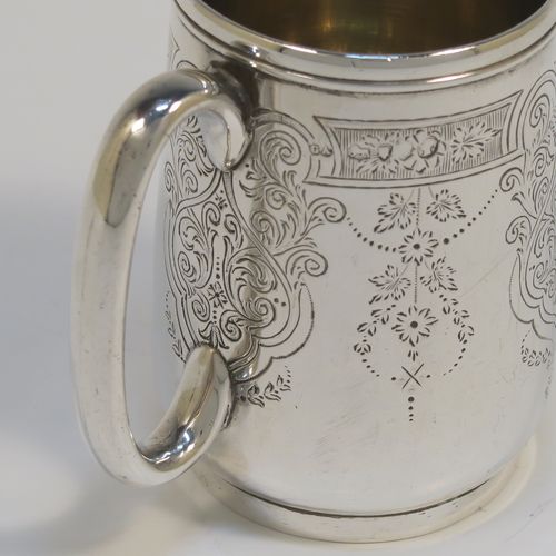 A very pretty Antique Victorian Sterling Silver christening mug, having a round body with straight tapering sides and tucked under belly, with hand-engraved floral and scroll-work decoration, a plain loop handle, a gold-gilt interior, and all sitting on a collet foot. This beautiful silver christening mug was made by George Adams of London in 1878. The dimensions of this fine hand-made antique silver christening mug are height 8 cms (3 inches), diameter at lip 5 cms (2 inches), and it weighs approx. 93g (3 troy ounces).   