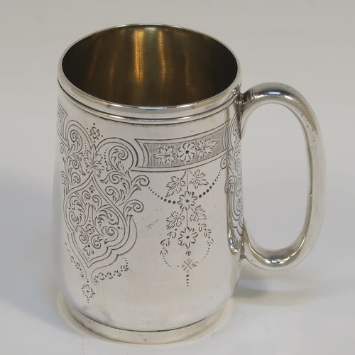 A very pretty Antique Victorian Sterling Silver christening mug, having a round body with straight tapering sides and tucked under belly, with hand-engraved floral and scroll-work decoration, a plain loop handle, a gold-gilt interior, and all sitting on a collet foot. This beautiful silver christening mug was made by George Adams of London in 1878. The dimensions of this fine hand-made antique silver christening mug are height 8 cms (3 inches), diameter at lip 5 cms (2 inches), and it weighs approx. 93g (3 troy ounces).   