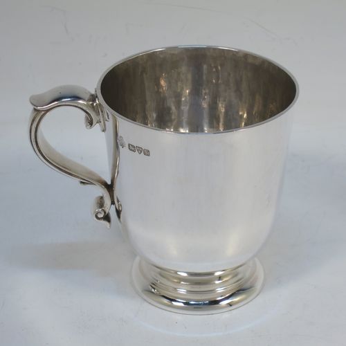 A handsome and heavy Antique Edwardian Sterling Silver christening mug, having a plain round straight-sided body with tucked under belly, a hand-hammered interior, a scroll handle with hand-chased reeded decoration, and sitting on a pedestal foot. Made by Jays of Chester in 1909. The dimensions of this fine hand-made antique silver christening mug are height 8 cms (3 inches), length 9.5 cms (3.75 inches), and it weighs approx. 161g (5.2 troy ounces).  