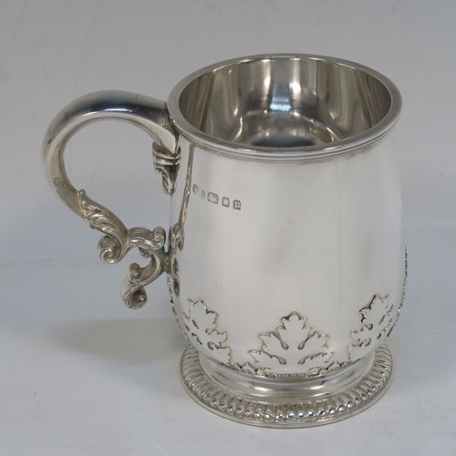 A handsome and unusual Sterling Silver christening mug, having a plain round body with tapering sides and tucked under belly with applied floral cut-card work, a scroll handle with applied leaf-work, and sitting on a pedestal foot with a pearl drop border. This elegant silver christening mug was made by Manoah Rhodes of London in 1930. The dimensions of this fine hand-made silver christening mug are height 9.5 cms (3.75 inches), length 11 cms (4.25 inches), and it weighs approx. 238g (7.7 troy ounces).   