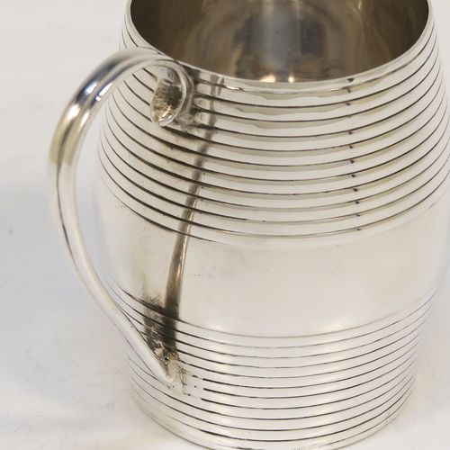 An elegant Antique Georgian Sterling Silver christening mug, having a round barrel-shaped body with two bands of hand-chased reeded decoration, a scroll side-handle, and sitting on a flat base. This handsome antique silver christening mug was made by James Jennings of London in 1780. The dimensions of this fine hand-made antique silver christening mug are height 6.5 cms (2.75 inches), length 8 cms (3 inches), and it weighs approx. 71g (2.3 troy ounces).  