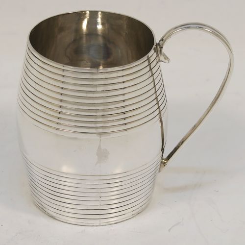 An elegant Antique Georgian Sterling Silver christening mug, having a round barrel-shaped body with two bands of hand-chased reeded decoration, a scroll side-handle, and sitting on a flat base. This handsome antique silver christening mug was made by James Jennings of London in 1780. The dimensions of this fine hand-made antique silver christening mug are height 6.5 cms (2.75 inches), length 8 cms (3 inches), and it weighs approx. 71g (2.3 troy ounces).  