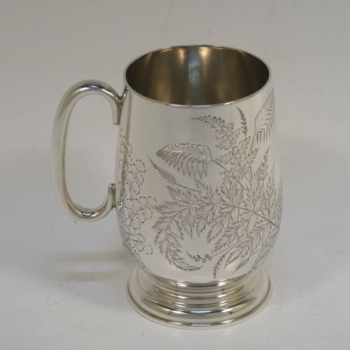 A very pretty Antique Victorian Sterling Silver christening mug, having a round body with straight tapering sides and tucked under belly, with hand-engraved ferns and gingko leaves decoration, a plain loop handle, and all sitting on a pedestal foot. This beautiful silver christening mug was made by Thomas Goodfellow of London in 1888. The dimensions of this fine hand-made antique silver christening mug are height 9.5 cms (3.75 inches), diameter at lip 6 cms (2.25 inches), and it weighs approx. 147g (4.7 troy ounces).  