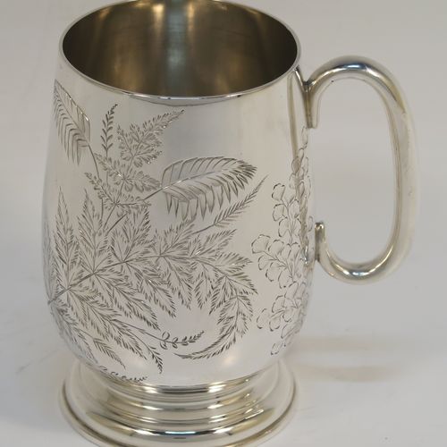 A very pretty Antique Victorian Sterling Silver christening mug, having a round body with straight tapering sides and tucked under belly, with hand-engraved ferns and gingko leaves decoration, a plain loop handle, and all sitting on a pedestal foot. This beautiful silver christening mug was made by Thomas Goodfellow of London in 1888. The dimensions of this fine hand-made antique silver christening mug are height 9.5 cms (3.75 inches), diameter at lip 6 cms (2.25 inches), and it weighs approx. 147g (4.7 troy ounces).  