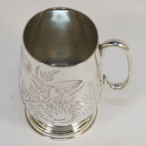 A very pretty Antique Victorian Sterling Silver christening mug, having a round body with straight tapering sides and tucked under belly, with hand-engraved ferns and gingko leaves decoration, a plain loop handle, and all sitting on a pedestal foot. This beautiful silver christening mug was made by Thomas Goodfellow of London in 1888. The dimensions of this fine hand-made antique silver christening mug are height 9.5 cms (3.75 inches), diameter at lip 6 cms (2.25 inches), and it weighs approx. 147g (4.7 troy ounces).  