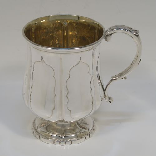 An elegant Antique early Victorian Sterling Silver christening mug, having a bellied body with hand-chased fluted and panelled decoration, a scroll handle with anthemion leaf thumb-piece, a gold-gilt interior, and all sitting on a pedestal foot. This handsome silver christening mug was made by the Edward Burton of London in 1837. The dimensions of this fine hand-made antique silver christening mug are height 10 cms (4 inches), length 10 cms (4 inches), and it weighs approx. 141g (4.5 troy ounces).   