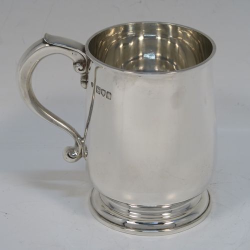 A very handsome Antique Sterling Silver half-pint tankard style christening mug, having a plain round bellied body, a scroll handle with thumb-piece, and sitting on a pedestal foot. This elegant antique silver mug was made by Holland, Aldwinkle, and Slater of London in 1912. The dimensions of this fine hand-made antique silver christening mug tankard are height 10 cms (4 inches), diameter at top 7 cms (2.75 inches), and it weighs approx. 240g (7.7 troy ounces).   