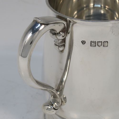 A very handsome Antique Sterling Silver half-pint tankard style christening mug, having a plain round bellied body, a scroll handle with thumb-piece, and sitting on a pedestal foot. This elegant antique silver mug was made by Holland, Aldwinkle, and Slater of London in 1912. The dimensions of this fine hand-made antique silver christening mug tankard are height 10 cms (4 inches), diameter at top 7 cms (2.75 inches), and it weighs approx. 240g (7.7 troy ounces).   