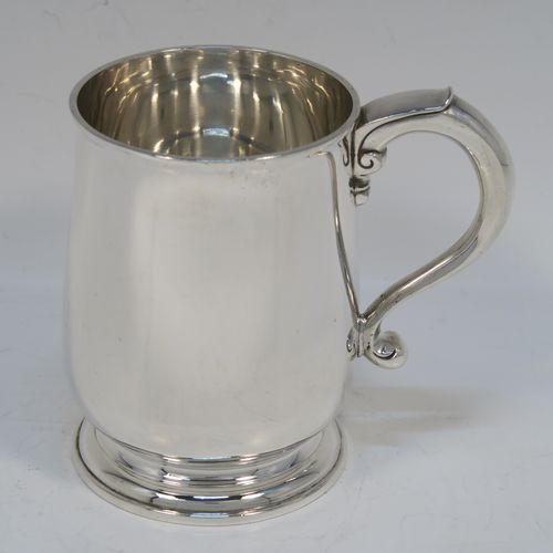 A very handsome Antique Sterling Silver half-pint tankard style christening mug, having a plain round bellied body, a scroll handle with thumb-piece, and sitting on a pedestal foot. This elegant antique silver mug was made by Holland, Aldwinkle, and Slater of London in 1912. The dimensions of this fine hand-made antique silver christening mug tankard are height 10 cms (4 inches), diameter at top 7 cms (2.75 inches), and it weighs approx. 240g (7.7 troy ounces).   