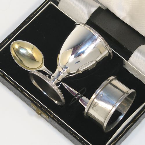 A handsome Sterling Silver three-piece christening set, consisting of a plain round napkin ring, a plain round egg cup with applied floral and scroll borders and a gold-gilt interior, and a plain Hanoverian pattern spoon with a gold-gilt bowl, all in their original cream satin and black velvet-lined presentation box. This elegant christening set was made by Turner and Simpson Birmingham in 1960 (the napkin ring was made by Henry Matthews of Birmingham in 1935). The dimensions of this fine hand-made silver christening set are length of spoon 10 cms (4 inches), diameter of napkin ring 4.5 cms (1.75 inches), height of egg cup 6.5 cms (2.75 inches), and the total weight is approx. 56g (1.8 troy ounces).   