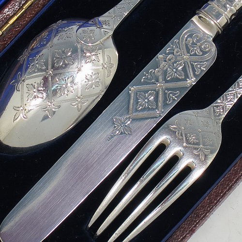 An Antique Victorian Sterling Silver christening set, having a knife, fork, and spoon, all hand-engraved with geometrical and floral work, and all sitting in their original dark blue satin and velvet-lined presentation box. Made by George Adams of London in 1871. The dimensions of this fine hand-made antique silver christening set are length of knife 19 cms (7.5 inches), with a total weight of approx. 100g (3 troy ounces).    