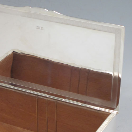 Sterling silver Art Deco style cigarette / cigar table box, having a very plain rectangular body with straight sides, hinged lid with thumb-piece, with engine-turned bands on inside border and lid, a wooden cedar-lined interior, and all sitting on four stepped corner feet. Made by J. B. Chatterley & Sons Ld., of Birmingham in 1955. The dimensions of this fine hand-made silver table box are length 17 cms (6.75 inches), height 6 cms (2.3 inches), and width 9.5 cms (3.75 inches).