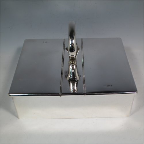 A Sterling Silver partners table cigar box, having a large plain rectangular body, with double hinged compartments opened by a mechanical carrying handle, and cedar wood-lined interiors. Made in London in 1933. The dimensions of this fine hand-made silver table cigar box are length 21 cms (8.25 inches), width 17 cms (6.75 inches), height inc. handle 14 cms (5.5 inches).   