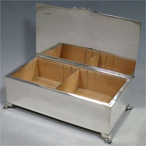 A Sterling Silver Art Deco style cigarette / cigar table box, having a very plain rectangular body with straight sides, a hinged lid with engine-turned decoration and thumb-piece, a wooden cedar-lined interior with divider, and all sitting on four stepped corner feet. Made by Mappin & Webb of London in 1929. The dimensions of this fine hand-made Art Deco silver table box are length 19 cms (7.5 inches), height 6 cms (2.5 inches), and width 10 cms (4 inches).    