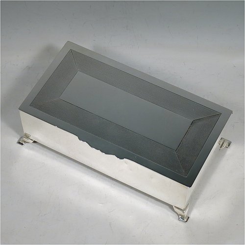 A Sterling Silver Art Deco style cigarette / cigar table box, having a very plain rectangular body with straight sides, a hinged lid with engine-turned decoration and thumb-piece, a wooden cedar-lined interior with divider, and all sitting on four stepped corner feet. Made by Mappin & Webb of London in 1929. The dimensions of this fine hand-made Art Deco silver table box are length 19 cms (7.5 inches), height 6 cms (2.5 inches), and width 10 cms (4 inches).    