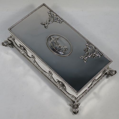 A very handsome and unusual Neptune themed Antique Victorian Sterling Silver cigar / cigarette box, having a rectangular body with applied rope-twist borders, laurel-leaf swags, Neptune face masks, and inter-twined dolphins, a hinged lid with an applied central oval cartouche with a scene of Neptune, mermaids, and sea-horses, a varnished wood-lined interior, and all sitting on four cast dolphin feet. Made by Reid and Sons of London in 1901. The dimensions of this fine hand-made antique silver table box are length 26 cms (10 inches), width 14 cms (5.5 inches), and height 8 cms (3 inches).    