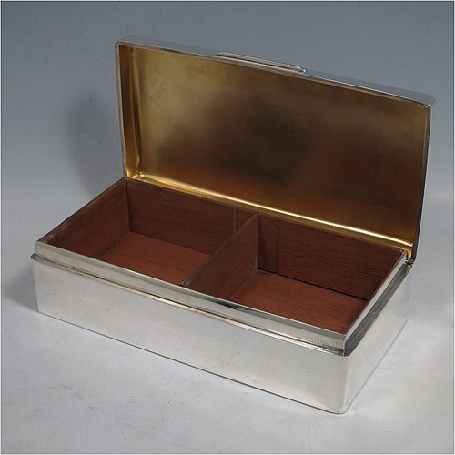 A Sterling Silver cigarette or cigar table box, having a plain rectangular body with nice rounded corners, a hinged lid having an applied thumb-piece, a gold-gilt interior to the lid, and a cedar wood-lined interior to the base, with a removable divider. Made by Alexander Clarke of London in 1925. The dimensions of this fine hand-made silver table box are length 17.5 cms (7 inches), width 9 cms (3.5 inches), and height 5 cms (2 inches).    