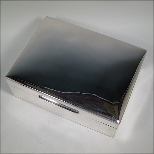 A very large Sterling Silver cigarette or cigar humidor table box, having a plain rectangular body with nice rounded corners, a hinged lid having an applied thumb-piece, a cedar wood-lined interior to lid and base, with two removable dividers. Made in London in 1923. The dimensions of this fine hand-made silver table box are length 30.5 cms (12 inches), width 23 cms (9 inches), and height 10 cms (4 inches). 