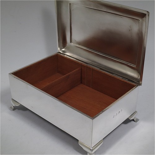 A large and very stylish Antique Edwardian Sterling Silver cigar / cigarette box, having a plain rectangular body, with a stepped and flat-topped hinged lid, a cedar wood-lined interior with internal divider, and all sitting on four cast stepped feet. Made by A. & J. Zimmerman of Birmingham in 1903. The dimensions of this fine hand-made antique silver table box are length 20 cms (8 inches), width 13.5 cms (5.25 inches), and height 9 cms (3.5 inches).   