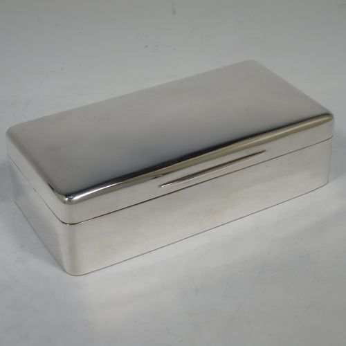 A handsome Antique Ewarian Sterling Silver cigarette / cigar table box, having a plain rectangular body with nice rounded corners, a hinged lid having an applied thumb-piece and gold-gilt inside, and a cedar wood-lined interior to the base, with a removable divider. Made by Goldsmiths and Silversmiths of London in 1909. The dimensions of this fine hand-made antique silver table cigar or cigarette box are length 18 cms (7 inches), width 9 cms (3.5 inches), and height 5 cms (2 inches).    