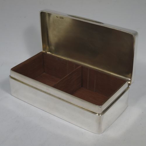 A handsome Antique Ewarian Sterling Silver cigarette / cigar table box, having a plain rectangular body with nice rounded corners, a hinged lid having an applied thumb-piece and gold-gilt inside, and a cedar wood-lined interior to the base, with a removable divider. Made by Goldsmiths and Silversmiths of London in 1909. The dimensions of this fine hand-made antique silver table cigar or cigarette box are length 18 cms (7 inches), width 9 cms (3.5 inches), and height 5 cms (2 inches).    