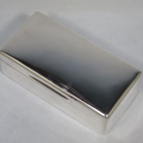 A handsome Antique Ewarian Sterling Silver cigarette / cigar table box, having a plain rectangular body with nice rounded corners, a hinged lid having an applied thumb-piece and gold-gilt inside, and a cedar wood-lined interior to the base, with a removable divider. Made by Goldsmiths and Silversmiths of London in 1909. The dimensions of this fine hand-made antique silver table cigar or cigarette box are length 18 cms (7 inches), width 9 cms (3.5 inches), and height 5 cms (2 inches).    