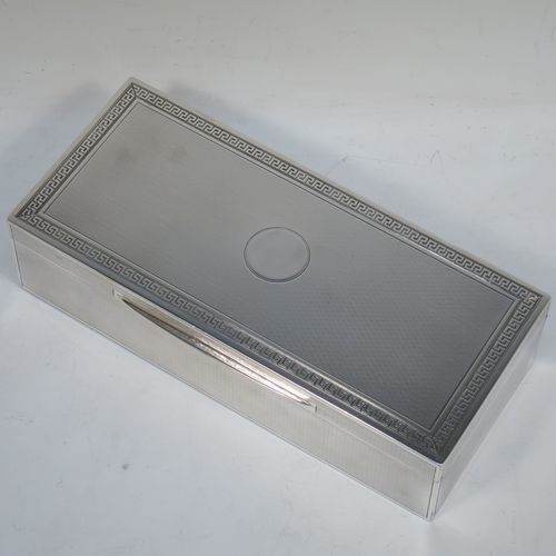 A very elegant Antique Sterling Silver cigarette / cigar table box, having a rectangular body with geometrically designed engine-turned decoration, a hinged lid with a central round vacant cartouche and a Greek-Key border, an applied thumb-piece, a gold-gilt and cedar wood-lined interior, and all sitting on a flat base. Made by Mappin and Webb of London in 1919. The dimensions of this fine hand-made antique silver table box are length 20 cms (8 inches), width 9 cms (3.5 inches), and height 5 cms (2 inches).   