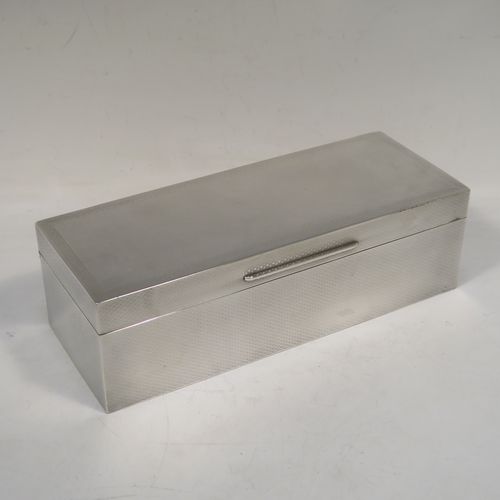 A very elegant Antique Sterling Silver cigarette / cigar table box, having a rectangular body with geometrically designed engine-turned decoration, a hinged lid with a Greek-Key border, an applied thumb-piece, a gold-gilt and cedar wood-lined interior, and all sitting on a flat base. This beautiful silver box was made by William Neale of Birmingham in 1923. The dimensions of this fine hand-made antique silver table box are length 23 cms (9 inches), width 9 cms (3.5 inches), and height 7 cms (2.75 inches). Please note that there is a slight imperfection on the lid surface due to the removal of a dent in the engine turning.  