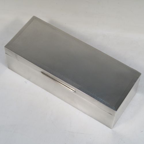 A very elegant Antique Sterling Silver cigarette / cigar table box, having a rectangular body with geometrically designed engine-turned decoration, a hinged lid with a Greek-Key border, an applied thumb-piece, a gold-gilt and cedar wood-lined interior, and all sitting on a flat base. This beautiful silver box was made by William Neale of Birmingham in 1923. The dimensions of this fine hand-made antique silver table box are length 23 cms (9 inches), width 9 cms (3.5 inches), and height 7 cms (2.75 inches). Please note that there is a slight imperfection on the lid surface due to the removal of a dent in the engine turning.  