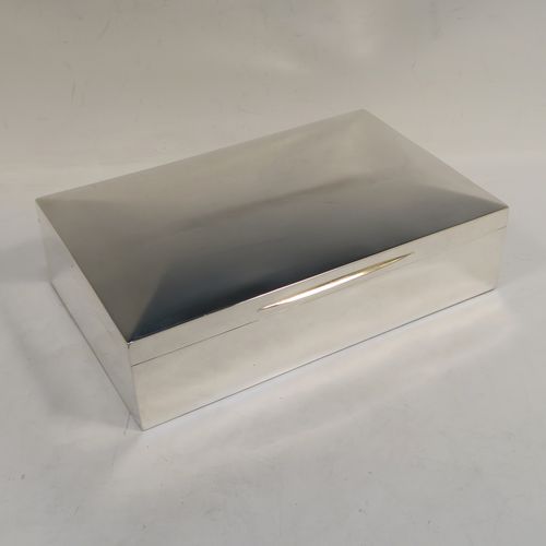 A very handsome and large Antique Edwardian Sterling Silver cigarette / cigar table box, having a plain rectangular body with chamfered  corners, a hinged lid having an applied thumb-piece, with a gold-gilt and cedar wood-lined interior to the base. This elegant antique silver table box was made by Mappin and Webb of Birmingham in 1910. The dimensions of this fine hand-made antique silver table cigar or cigarette box are length 24 cms (9.5 inches), width 15 cms (6 inches), and height 7 cms (2.75 inches).   