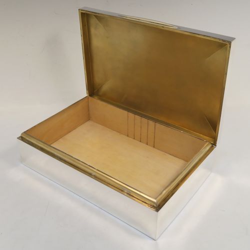 A very handsome and large Antique Edwardian Sterling Silver cigarette / cigar table box, having a plain rectangular body with chamfered  corners, a hinged lid having an applied thumb-piece, with a gold-gilt and cedar wood-lined interior to the base. This elegant antique silver table box was made by Mappin and Webb of Birmingham in 1910. The dimensions of this fine hand-made antique silver table cigar or cigarette box are length 24 cms (9.5 inches), width 15 cms (6 inches), and height 7 cms (2.75 inches).   