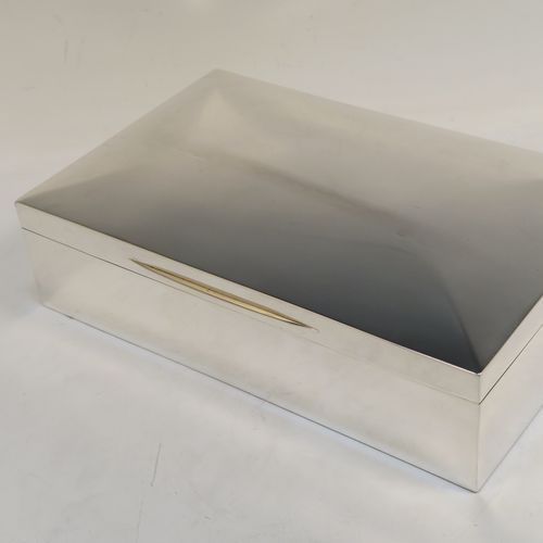 A very handsome and large Antique Edwardian Sterling Silver cigarette / cigar table box, having a plain rectangular body with chamfered  corners, a hinged lid having an applied thumb-piece, with a gold-gilt and cedar wood-lined interior to the base. This elegant antique silver table box was made by Mappin and Webb of Birmingham in 1910. The dimensions of this fine hand-made antique silver table cigar or cigarette box are length 24 cms (9.5 inches), width 15 cms (6 inches), and height 7 cms (2.75 inches).   